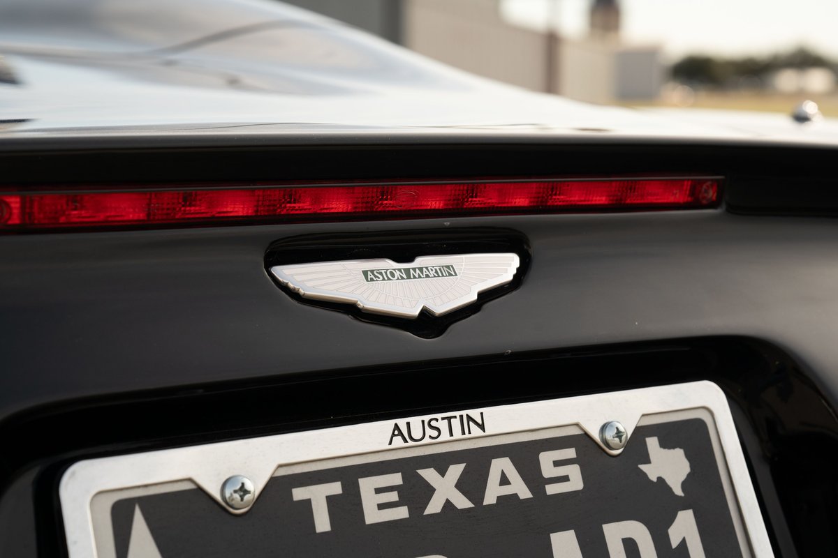 Rear view of a black 2003 Aston Martin DB AR1 Zagato with its badge and Texas license plate.