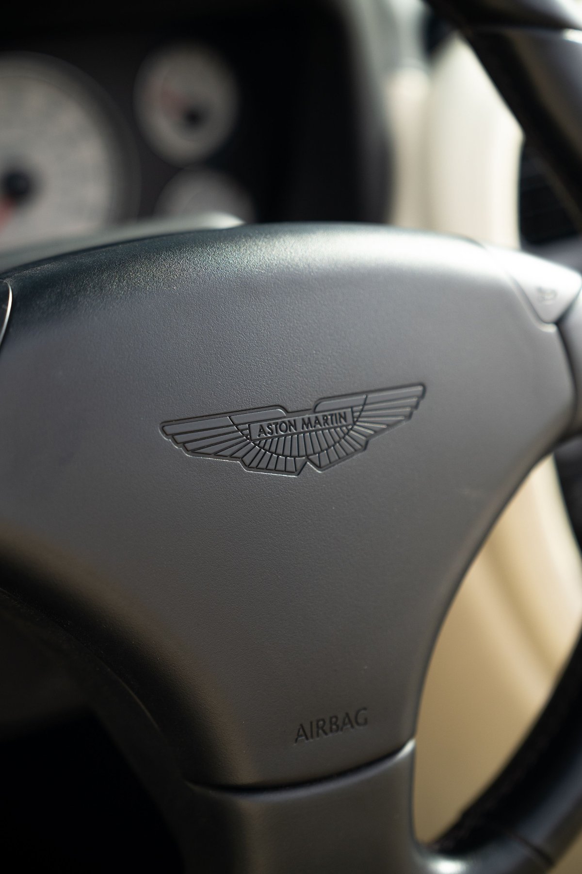Close-up of the Aston Martin logo on the steering wheel of a black 2003 Aston Martin DB AR1 Zagato.
