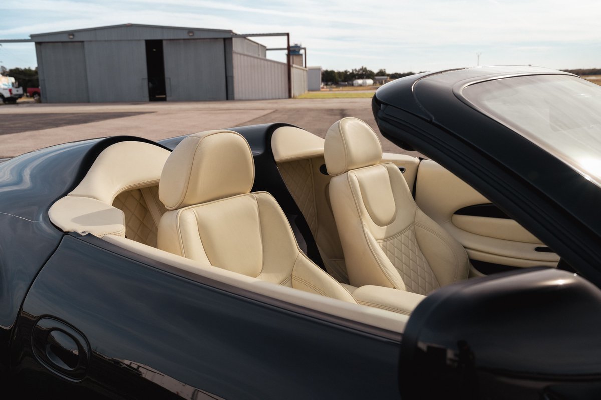 Black 2003 Aston Martin DB AR1 Zagato convertible interior with cream leather seats and diamond stitching.