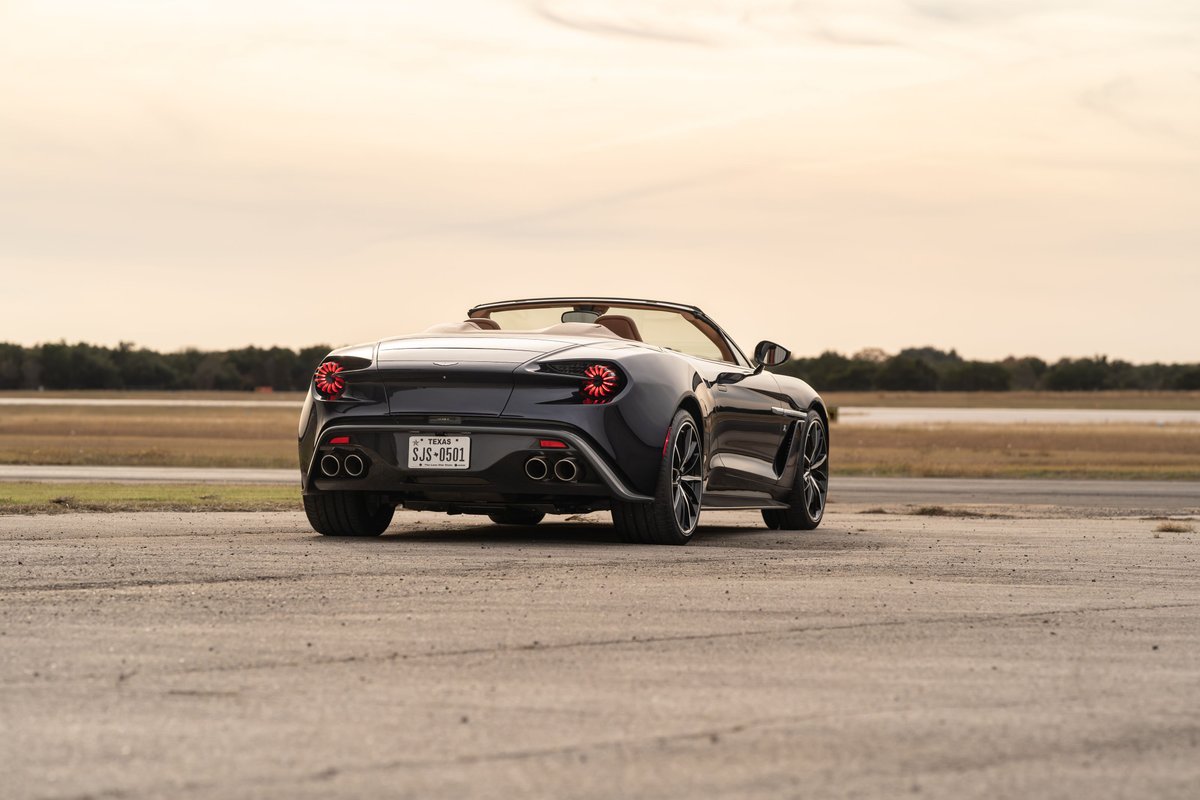 Rear view of a dark blue 2018 Aston Martin Vanquish Zagato convertible with quad exhaust and unique wheels.