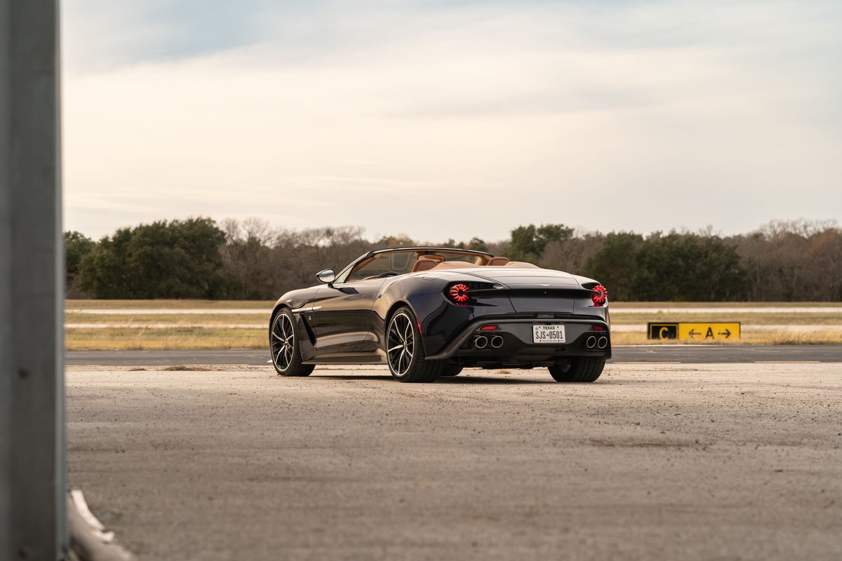 2018 Aston Martin Vanquish Zagato convertible in Orient Blue, showing rear 3/4 view, tan interior, black rims.