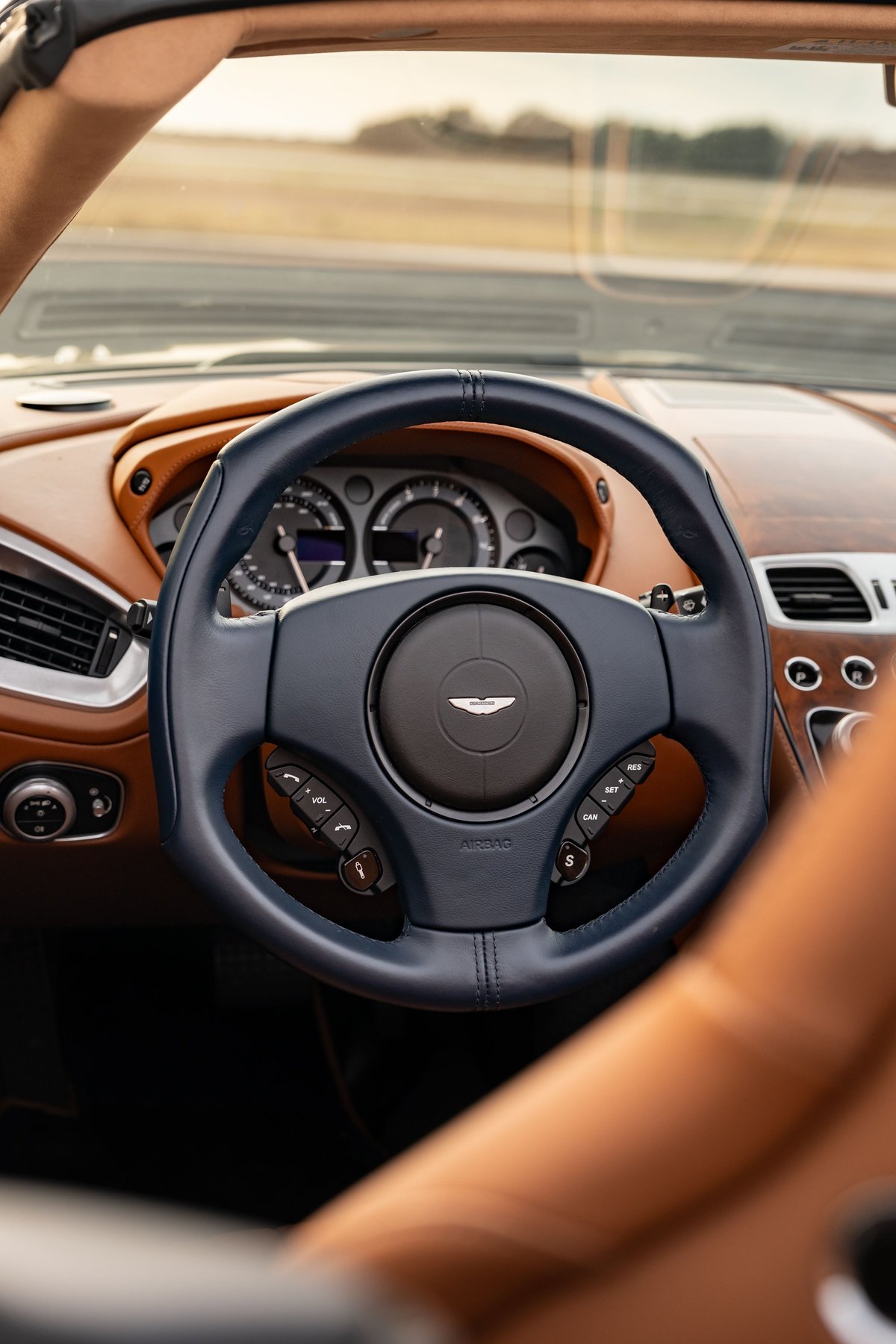 Interior of an Orient Blue 2018 Aston Martin Vanquish Zagato with tan leather trim and a dark blue steering wheel.