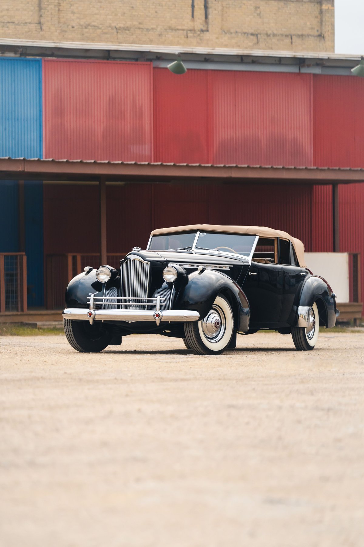 Black 1940 Packard Super Eight One-Eighty convertible with tan top and whitewall tires.