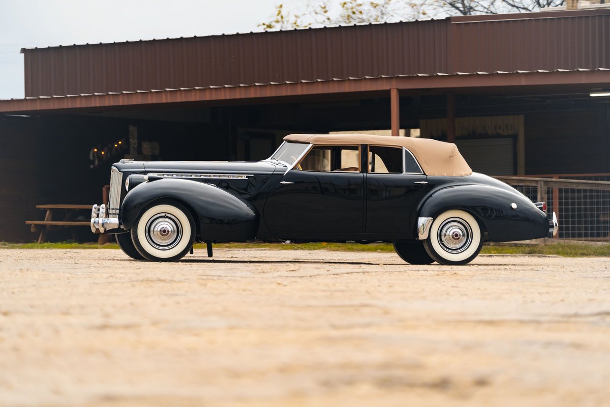 1940 Packard Super Eight One Eighty convertible coupe in black with tan top and whitewall rims.