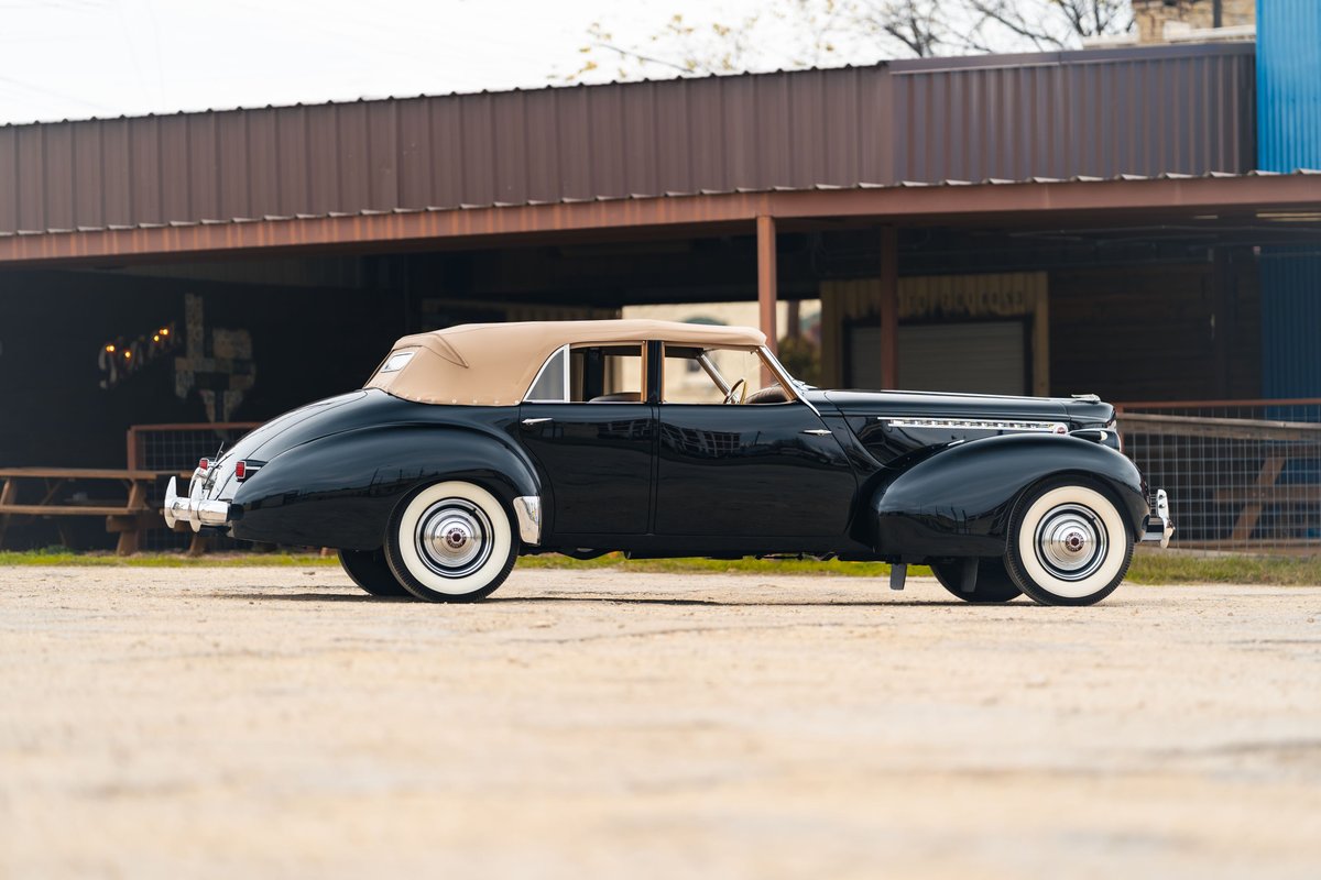 1940 Packard Super Eight One Eighty convertible in black with tan top and whitewall tires.