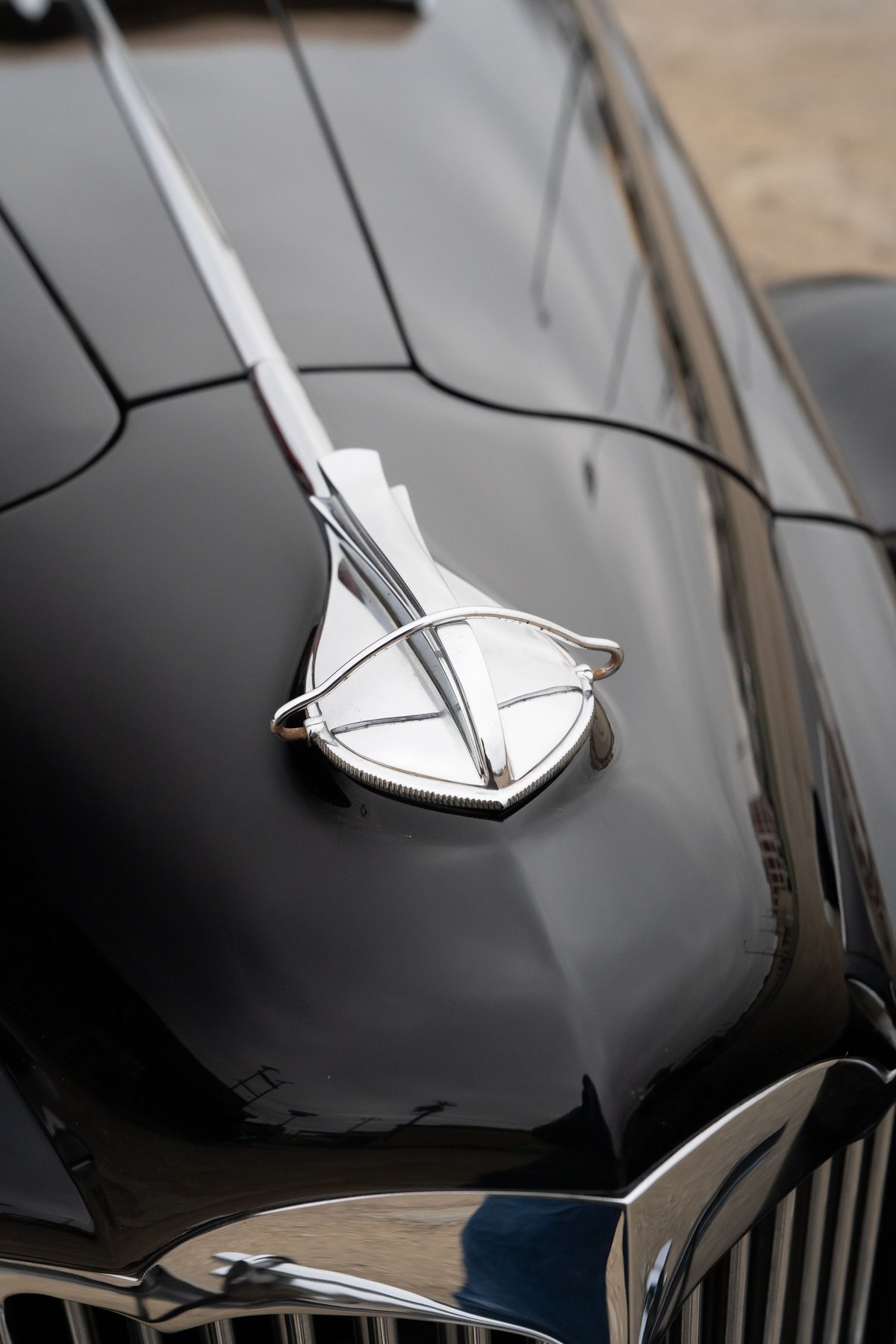 Close-up of a vintage black 1940 Packard Super Eight One Eighty hood ornament and grille.