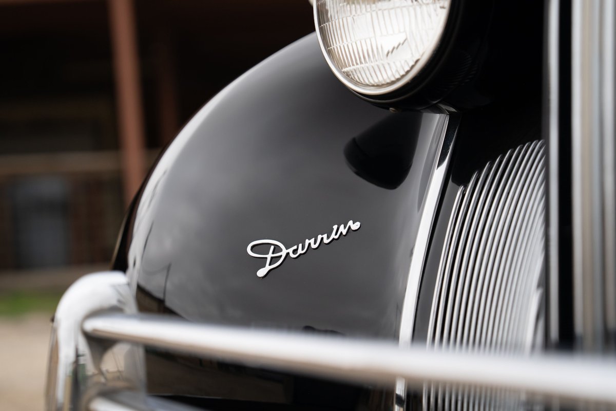 Close-up of the "Darrin" script badge on a black 1940 Packard Super Eight's fender.