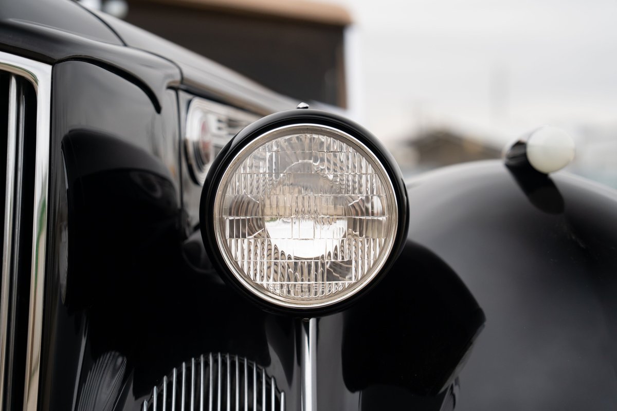 Close-up of a classic black 1940 Packard Super Eight 180's chrome grille and headlight.