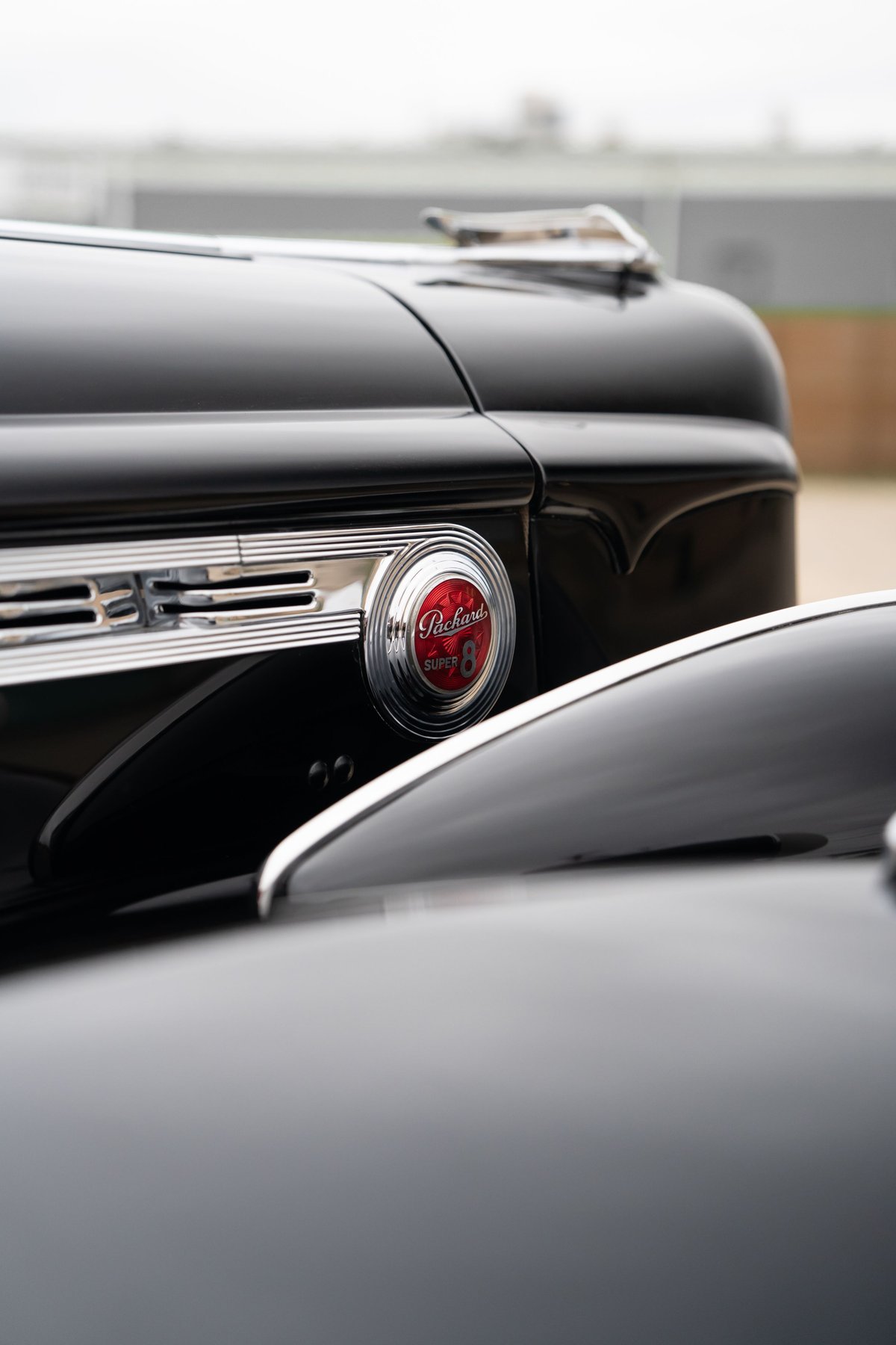 Close-up of a black Packard Super Eight's "36" grille and red "Packard Super 8" emblem.