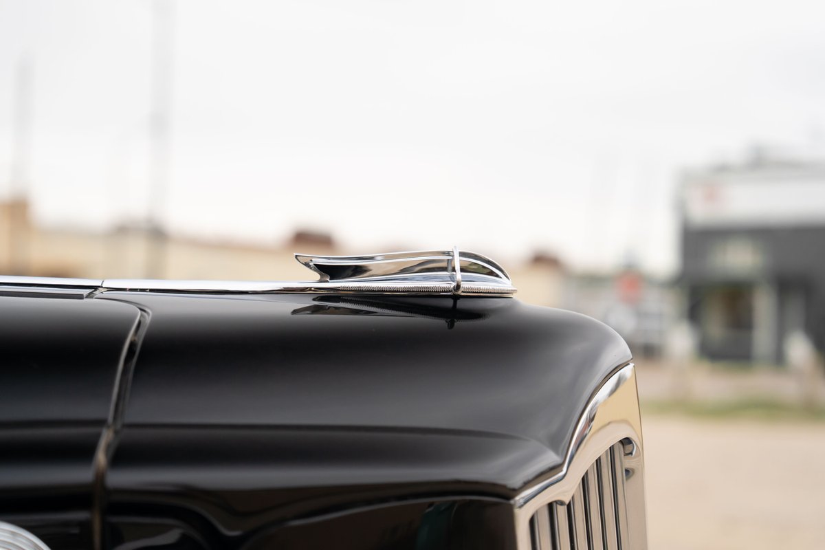 Close-up of a black 1940 Packard Super Eight's hood ornament and chrome trim.