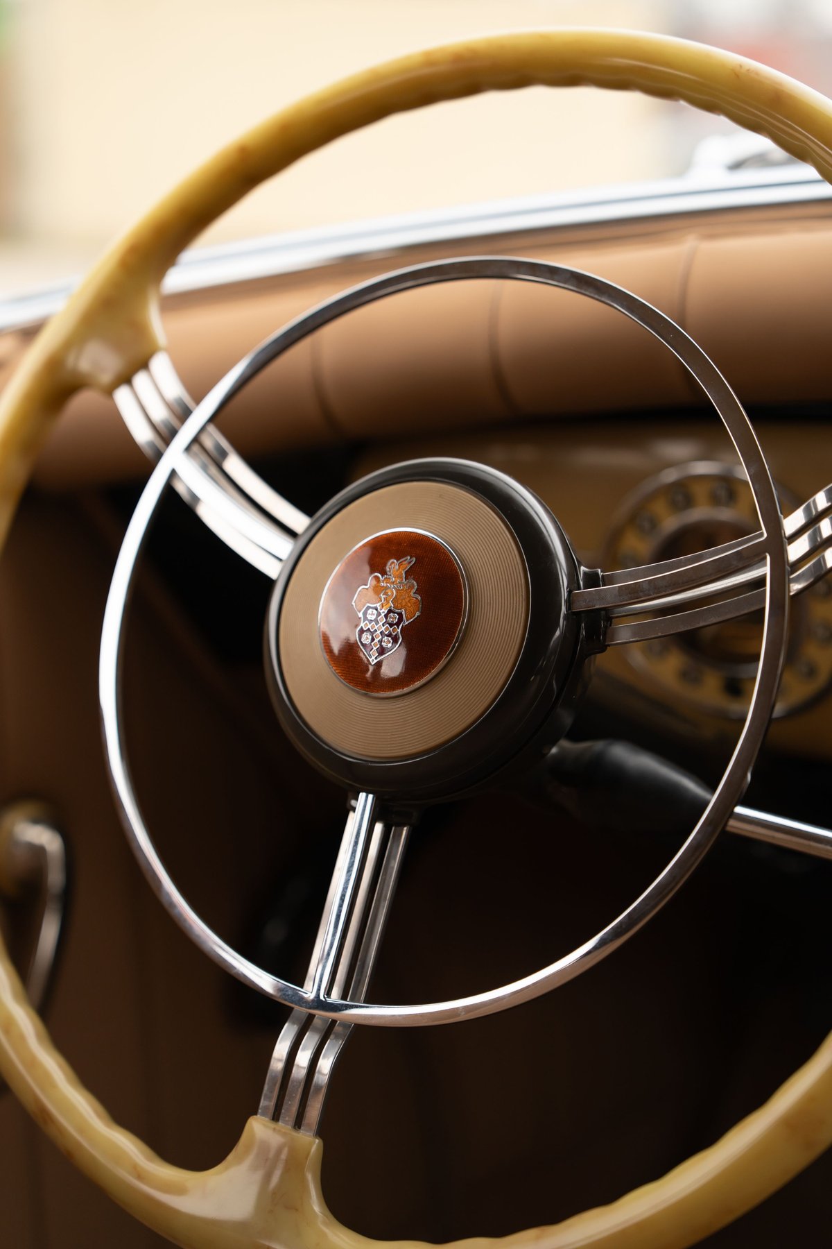 Vintage Packard Super Eight steering wheel with cream rim, chrome spokes, and enamel emblem.
