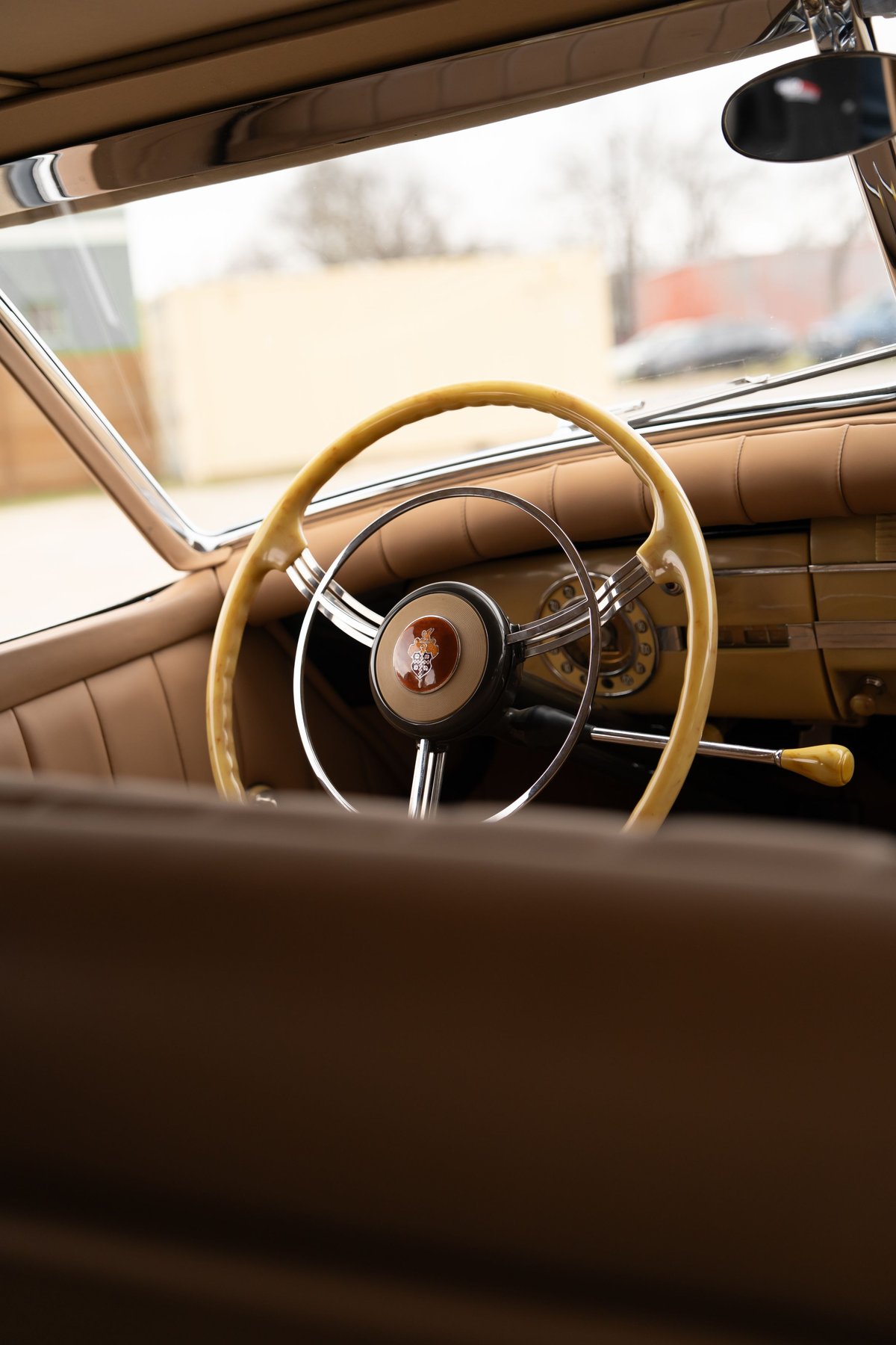 Close-up of a vintage Packard Super Eight's tan interior, featuring a tan steering wheel and dashboard trim.