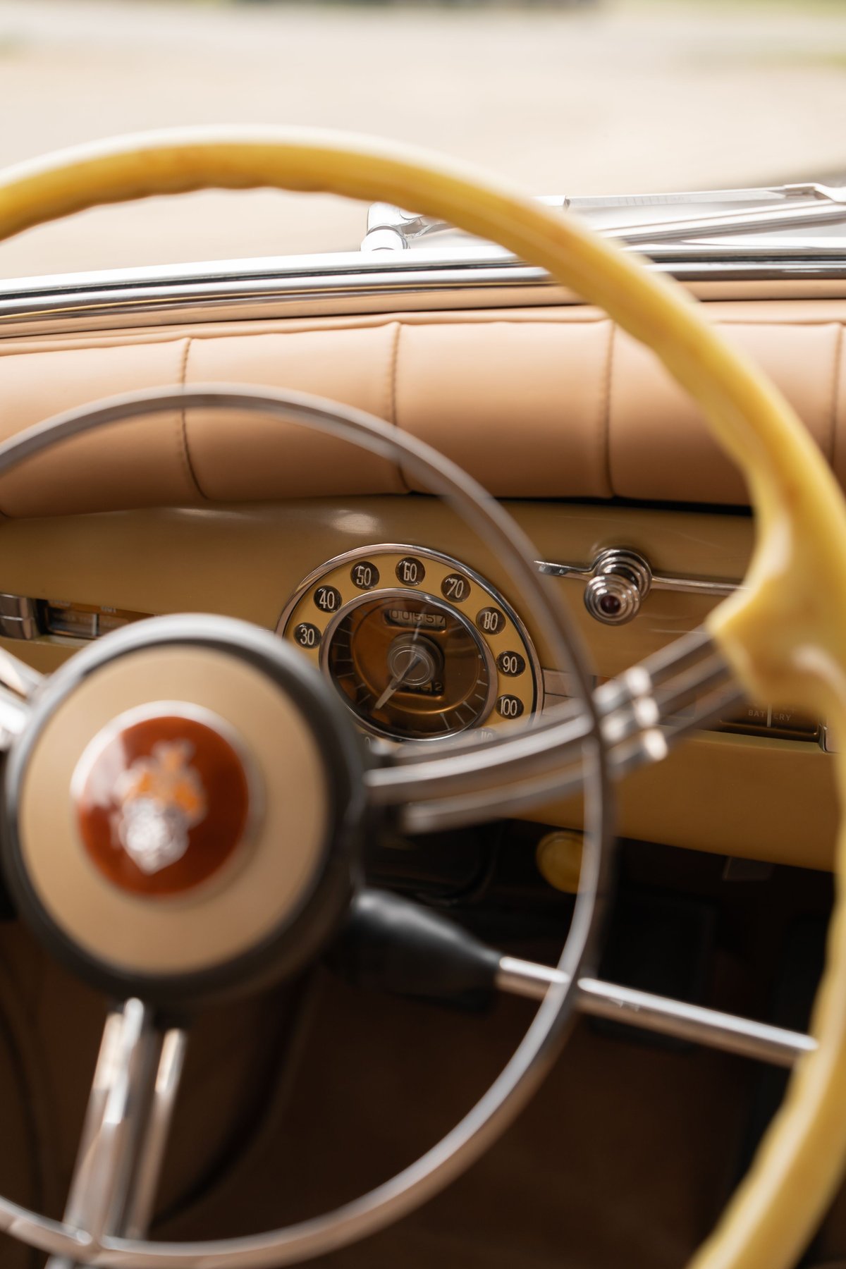 Close-up of a vintage yellow Packard Super Eight dashboard and steering wheel with chrome accents.