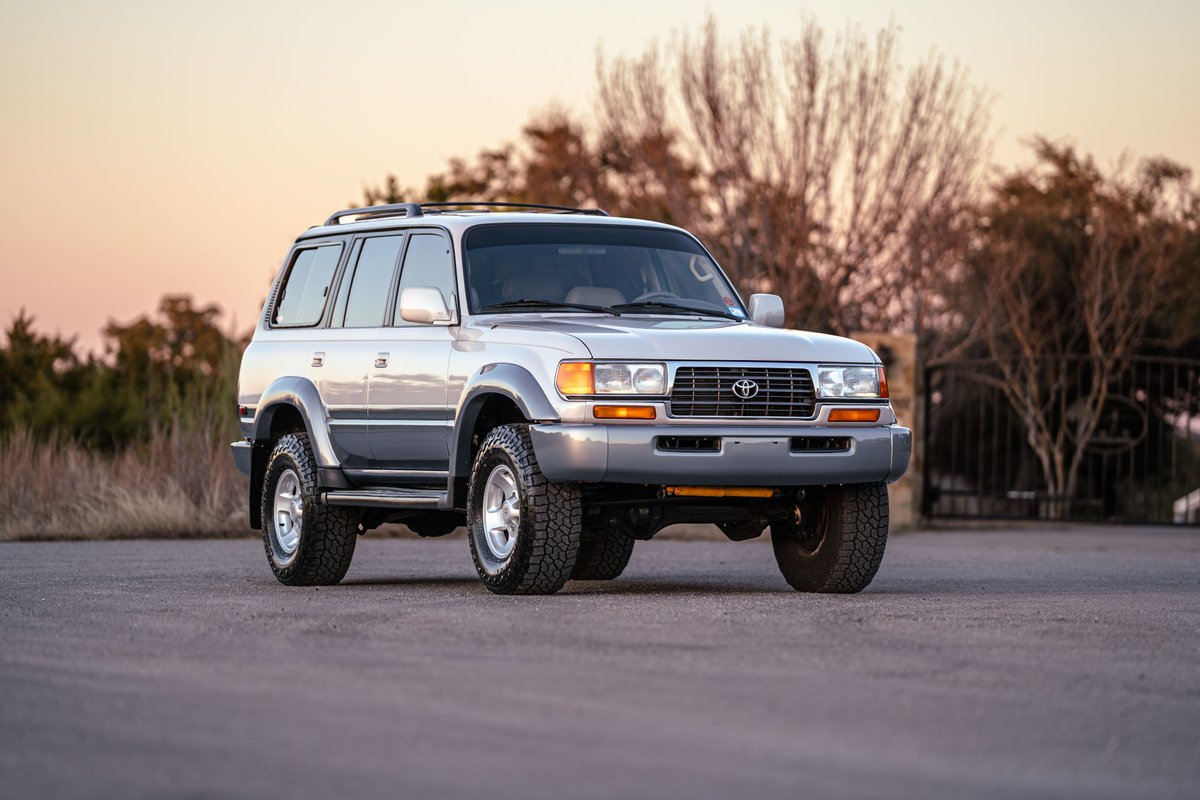 1997 Toyota Land Cruiser FZJ80 in Desert Dune Metallic with chrome rims and black trim.