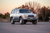 1997 Toyota Land Cruiser FZJ80 in Desert Dune Metallic with chrome rims and black trim.