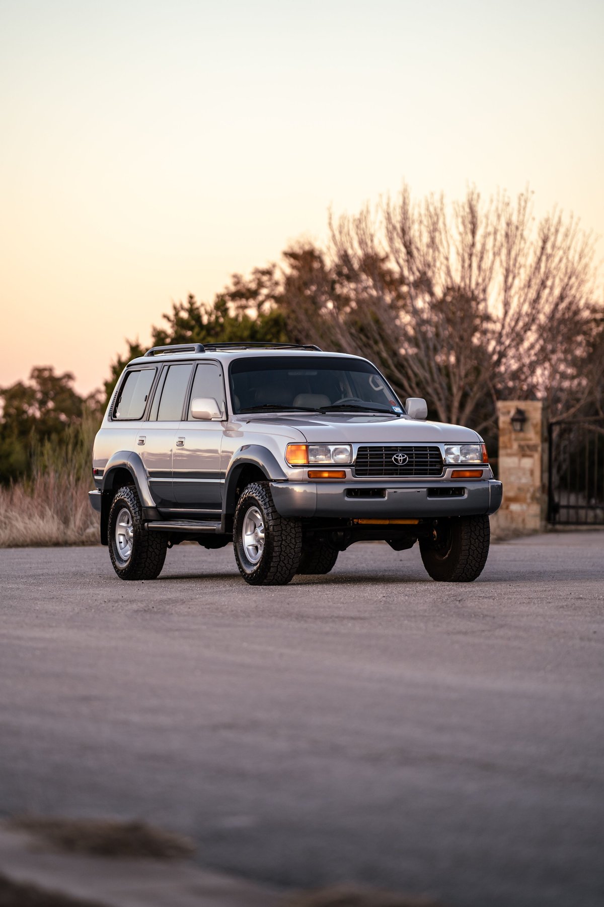 1997 Toyota Land Cruiser FZJ80 in Desert Dune Metallic, featuring chrome rims and matte black fender flares.