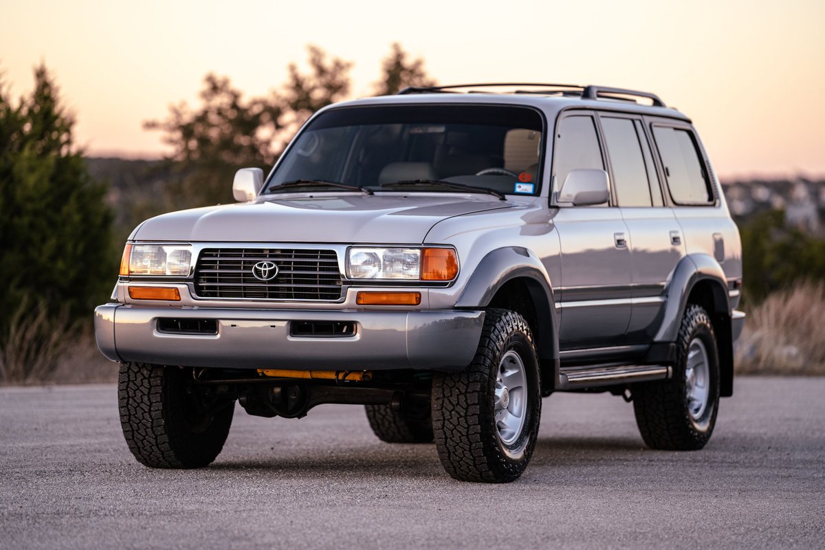 Silver 1997 Toyota Land Cruiser FJZ80 with grey fender flares, roof rack, and all-terrain tires.