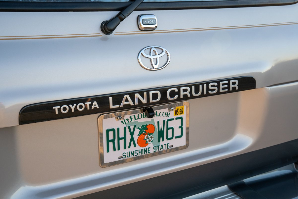 Silver 1997 Toyota Land Cruiser FJ80 rear with "LAND CRUISER" trim and Florida license plate.