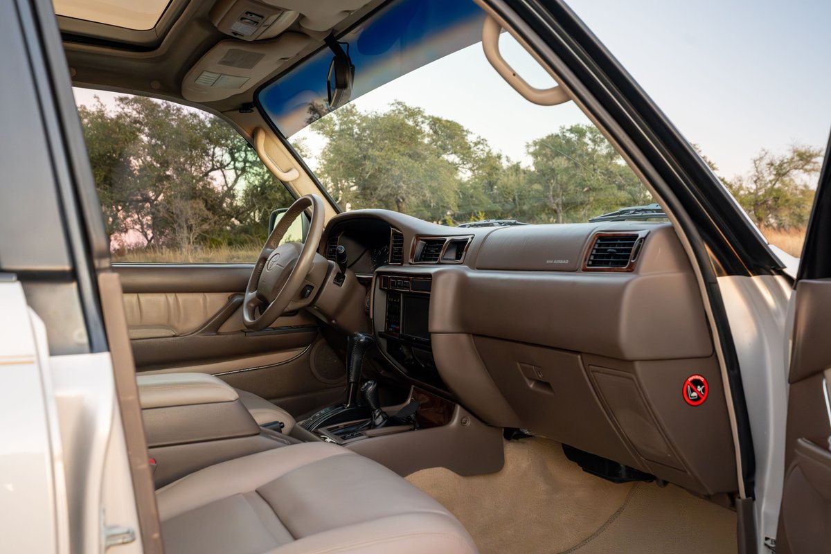 Interior view of a 1997 Toyota Land Cruiser FZJ80 in Desert Dune Metallic, showing leather seats & dashboard.