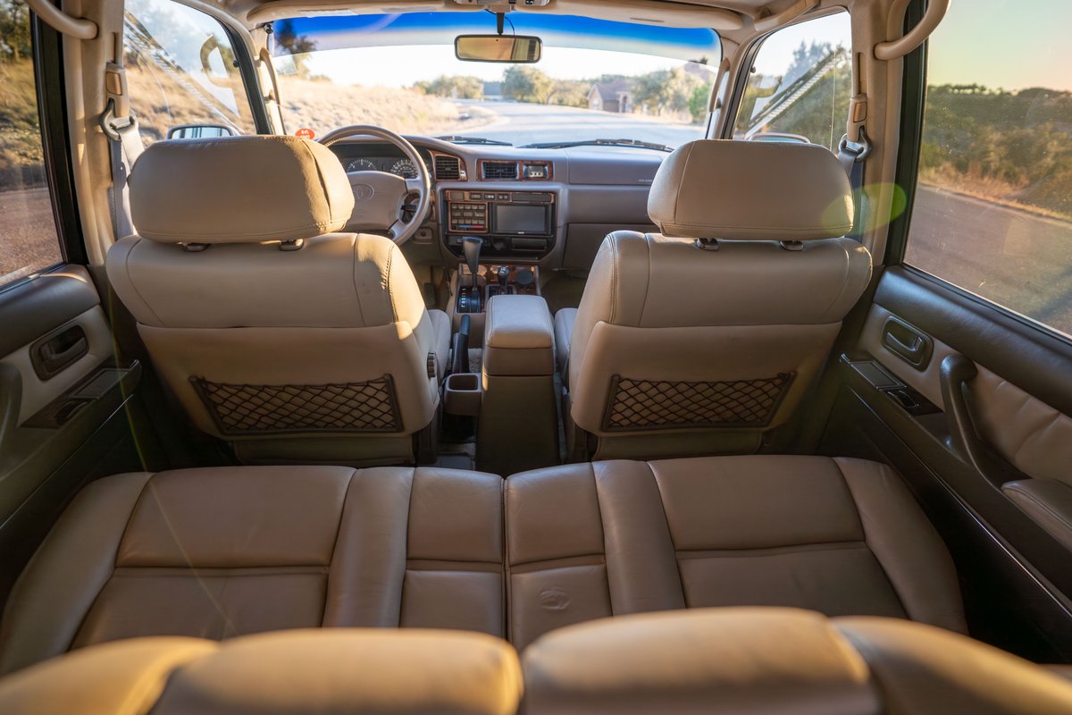 Interior shot of a 1997 Toyota Land Cruiser in Desert Dune Metallic, showcasing tan leather seats and dashboard trim.