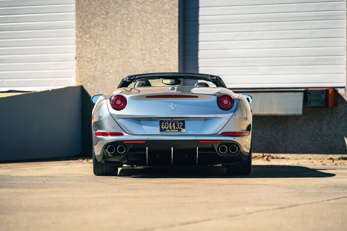 Rear view of a silver 2016 Ferrari California T with quad exhaust tips and black trim.