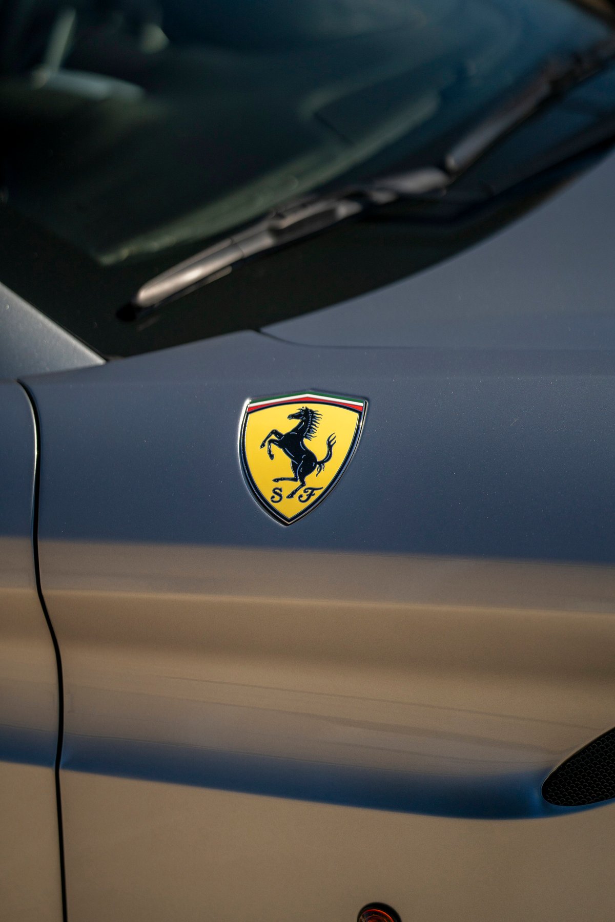 Close-up of a Ferrari Scuderia emblem on the fender of a silver 2016 Ferrari California T.