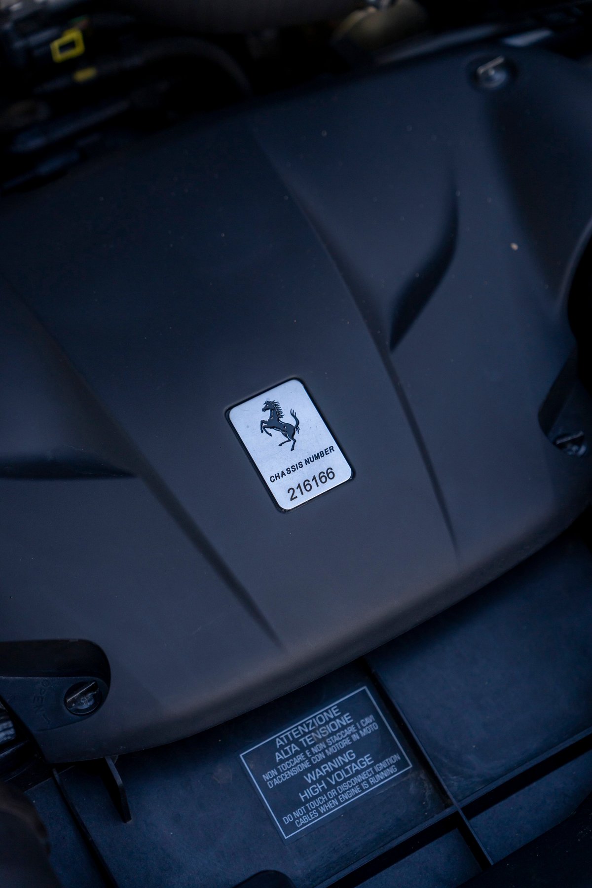 2016 Ferrari California T engine bay showing chassis number and high voltage warning sticker.