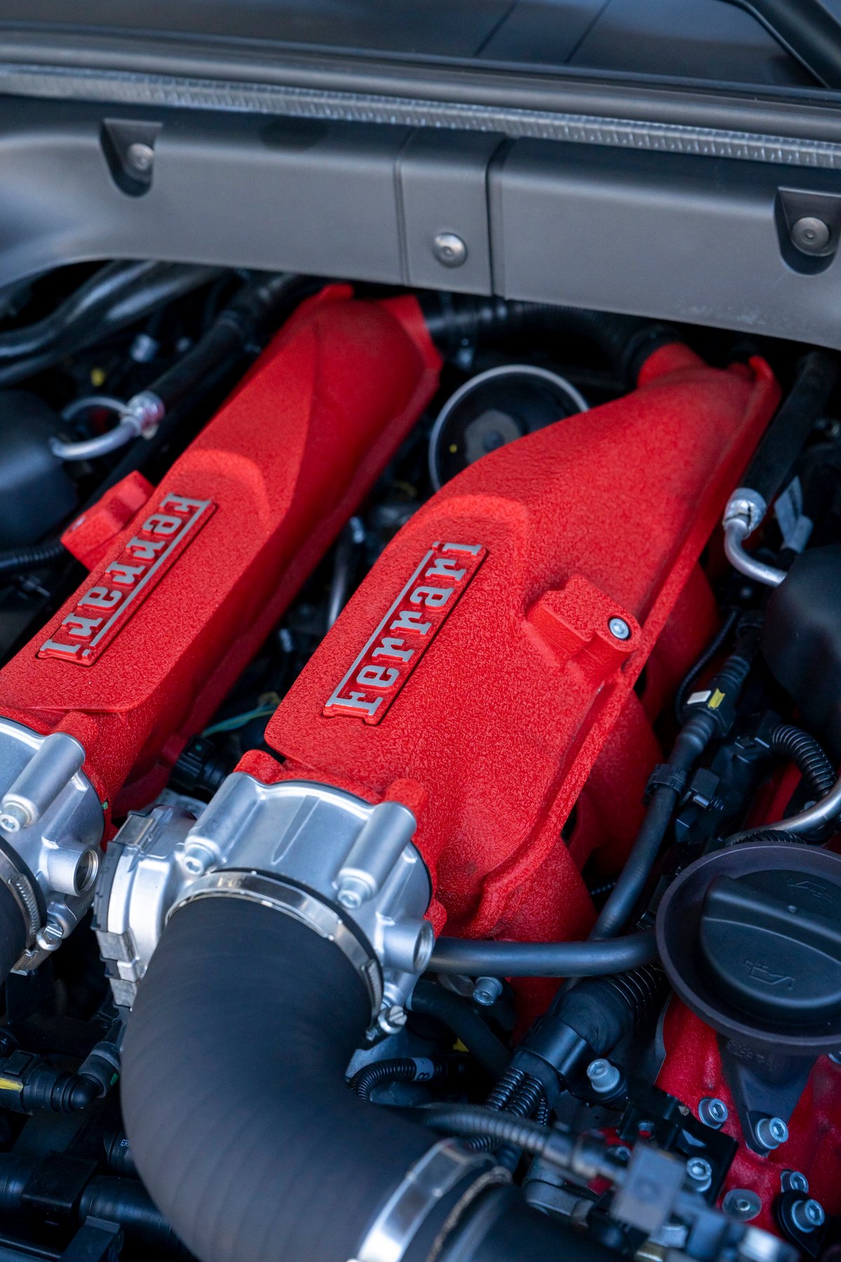 Close-up of a red Ferrari engine intake manifold with Ferrari badging.