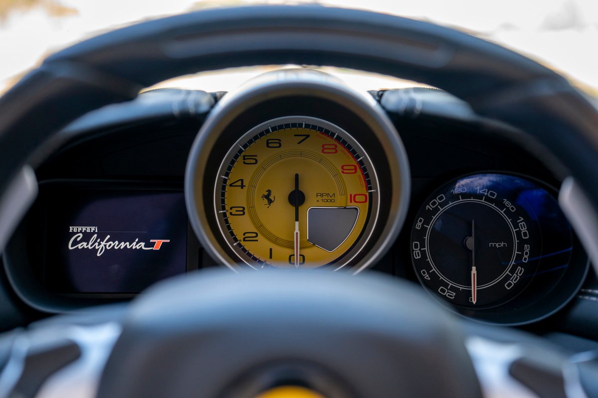 Close-up of a 2016 Ferrari California T dashboard with yellow tachometer and mph speedometer.