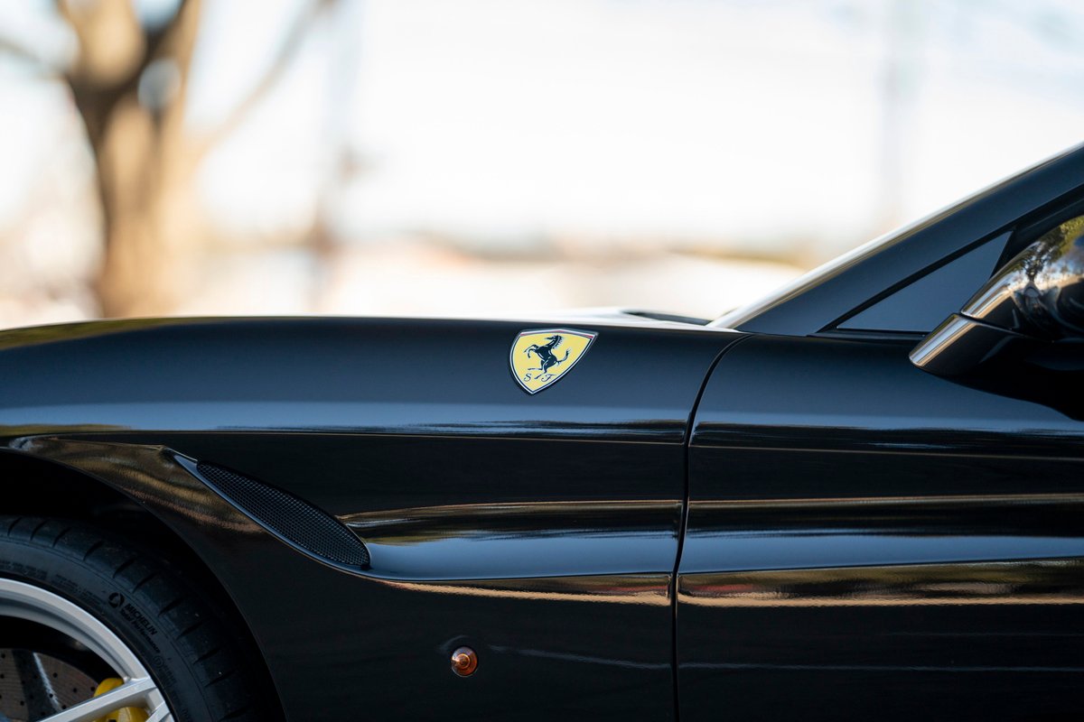 Close-up of a black Ferrari California T fender with the Prancing Horse emblem.