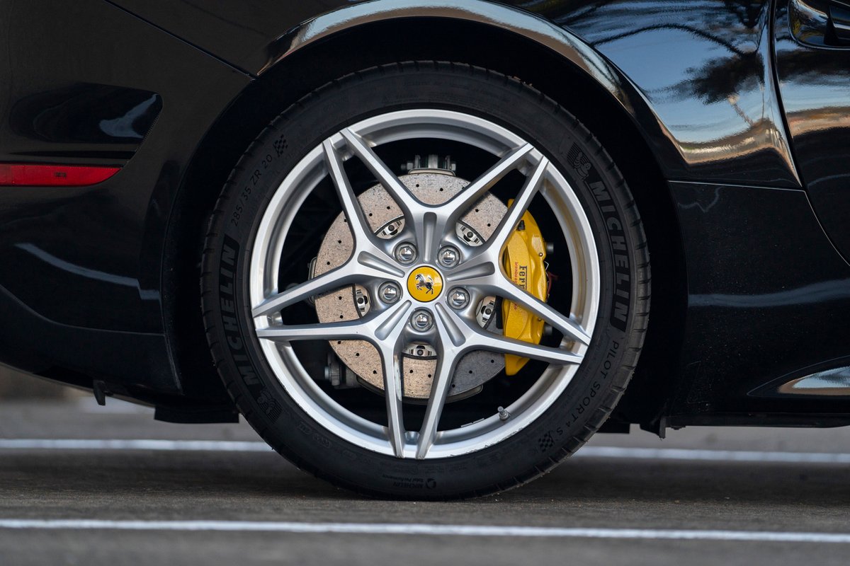 Close up of a silver Ferrari California T wheel with yellow brake calipers.