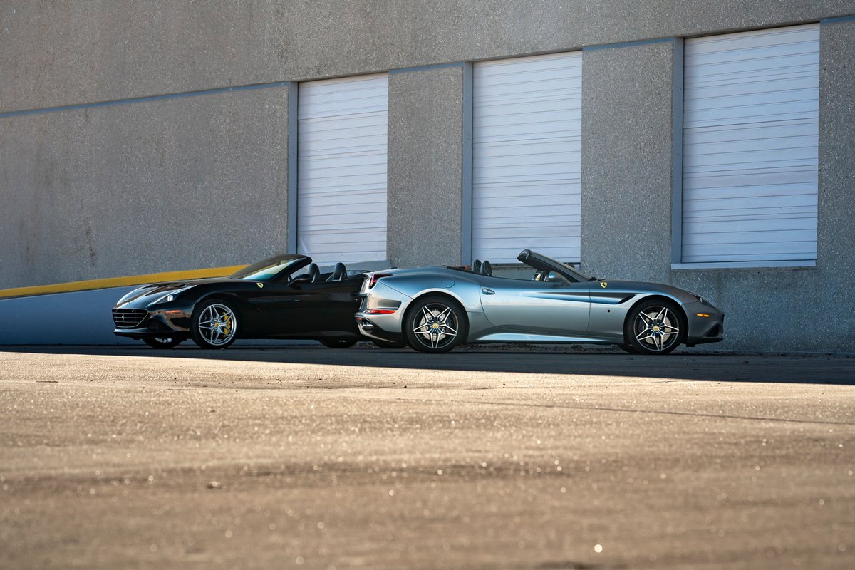 Black 2016 Ferrari California T convertible with five-spoke rims parked next to a silver one.