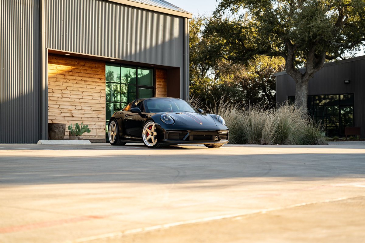 Black 2023 Porsche 911 Carrera 4 GTS with gold Rims, parked outside.