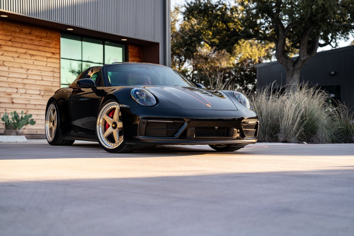 Black 2023 Porsche 911 Carrera 4 GTS with gold rims and red brake calipers.