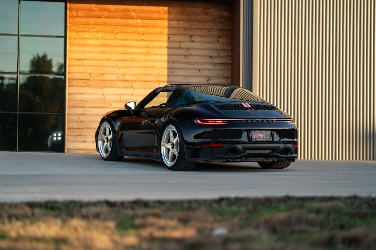 Black 2023 Porsche 911 Carrera 4 GTS with red stripe livery and silver multi-spoke rims.
