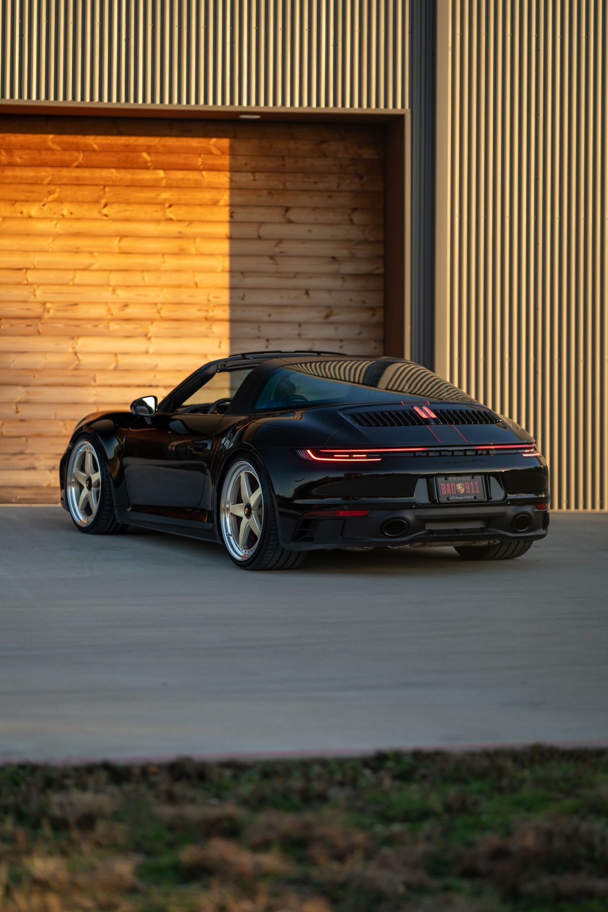 Black 2023 Porsche 911 Carrera 4 GTS Targa with red livery detail and custom rims.