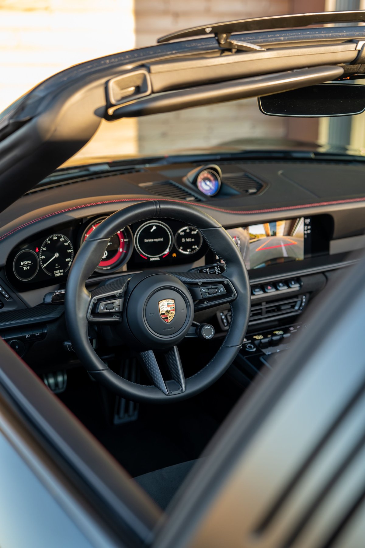 Black 2023 Porsche 911 Carrera 4 GTS interior, featuring a steering wheel, dashboard, and sport seats.
