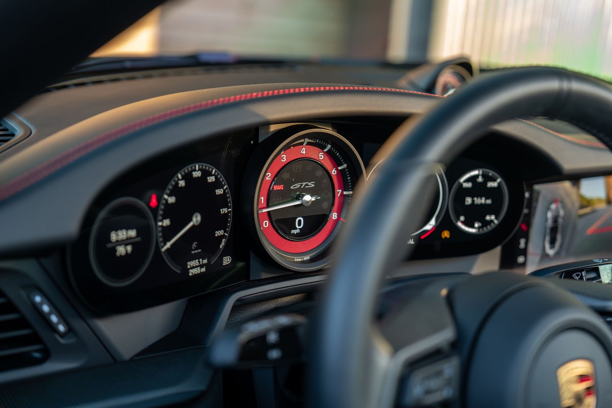 Black 2023 Porsche 911 Carrera 4 GTS interior dashboard and steering wheel.