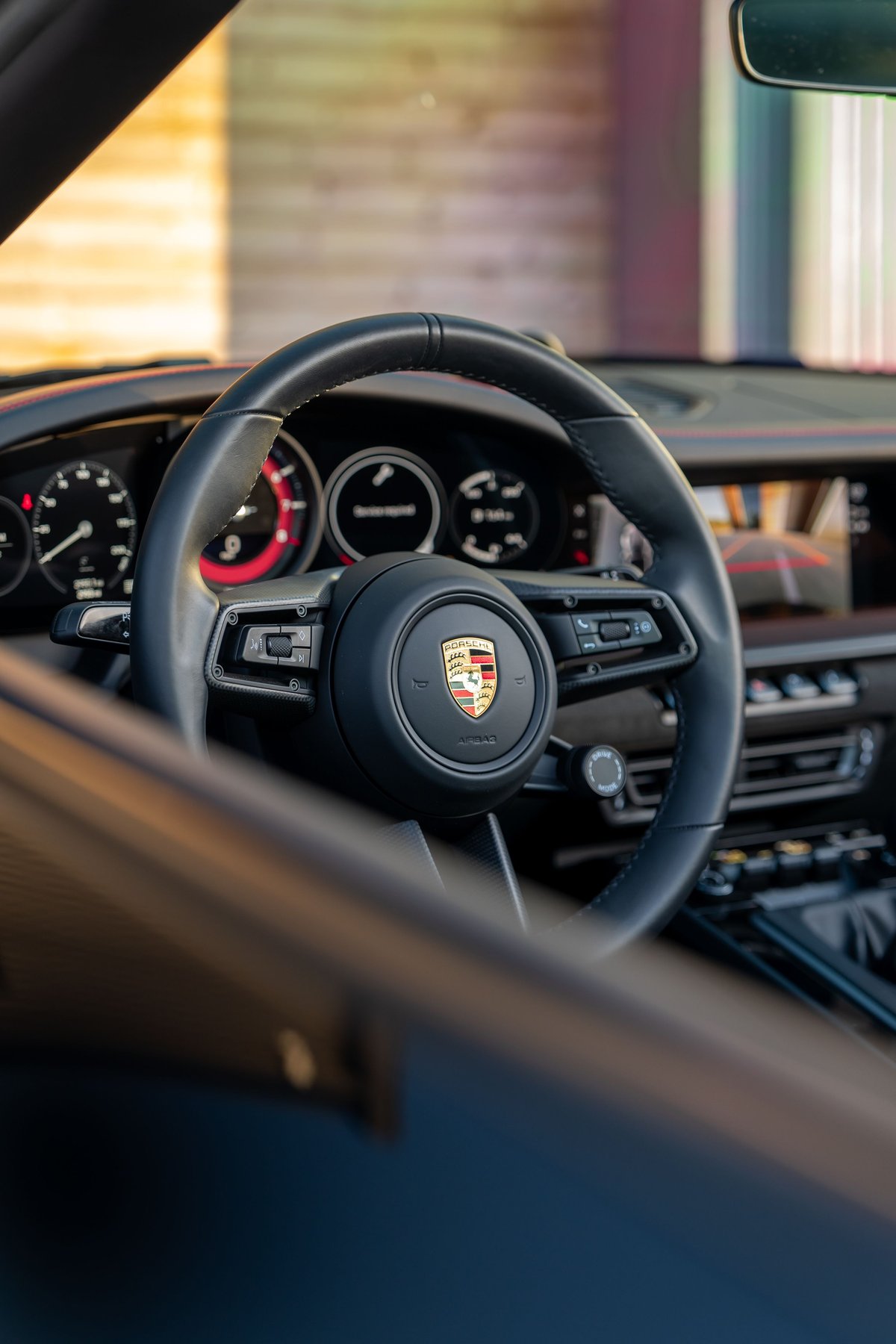 Black 2023 Porsche 911 Carrera 4 GTS interior, featuring the steering wheel, dashboard, and central infotainment screen.