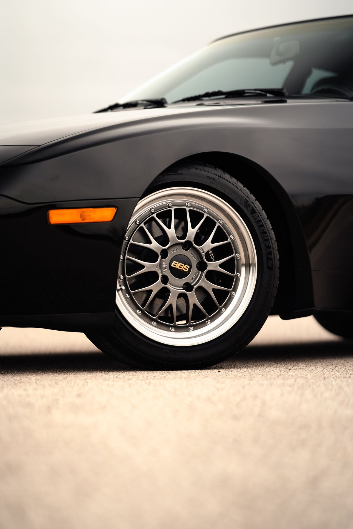 Black 1986 Porsche 944 Turbo front wheel with silver BBS rims.
