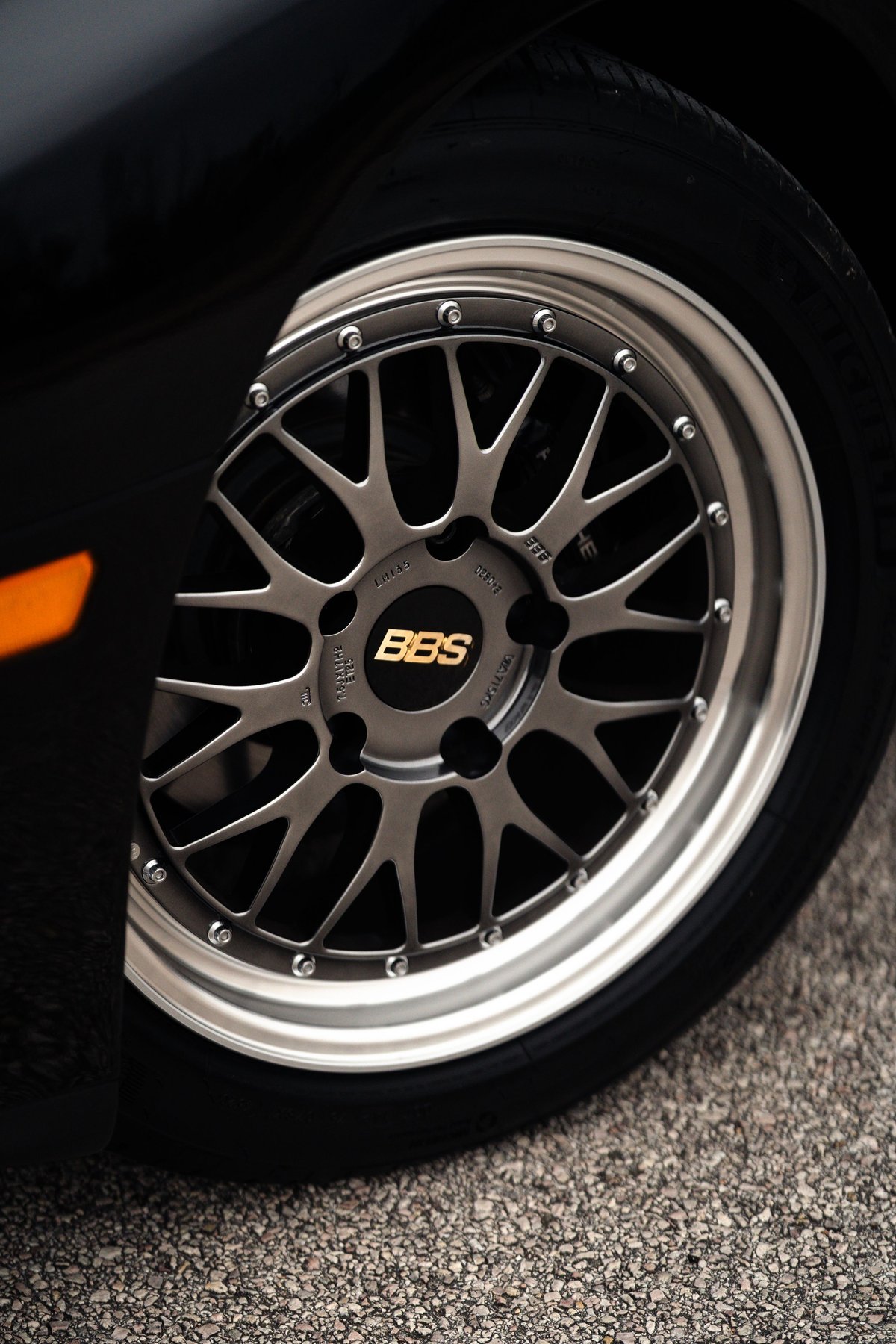Close-up of a black 1986 Porsche 944 Turbo's BBS wheel with gold logo.