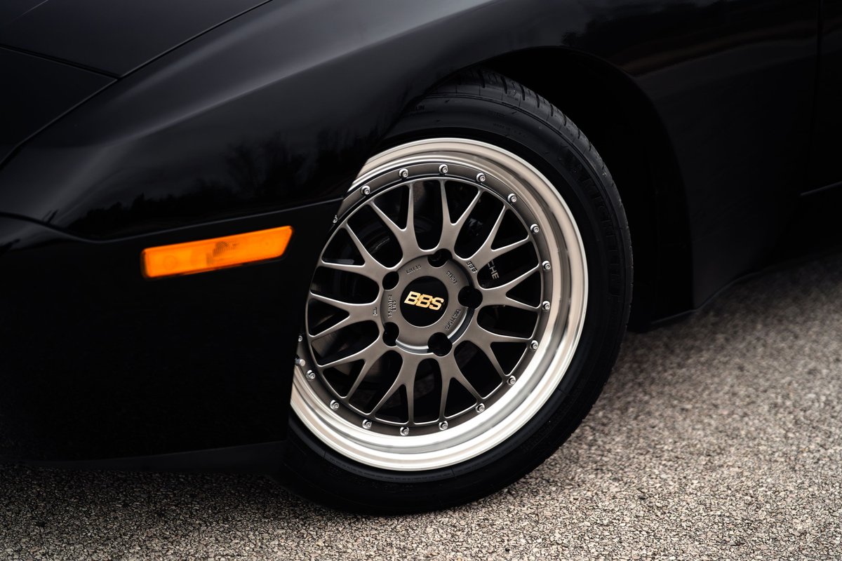 Close up of a black 1986 Porsche 944 Turbo's front wheel, featuring BBS rims and an orange turn signal.