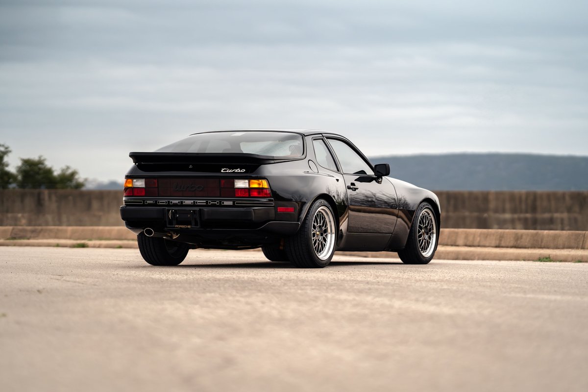 Black 1986 Porsche 944 Turbo rear 3/4 view with aftermarket rims.