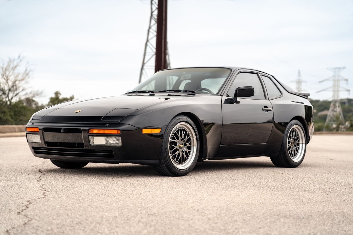 Black 1986 Porsche 944 Turbo with aftermarket BBS rims and a rear spoiler.