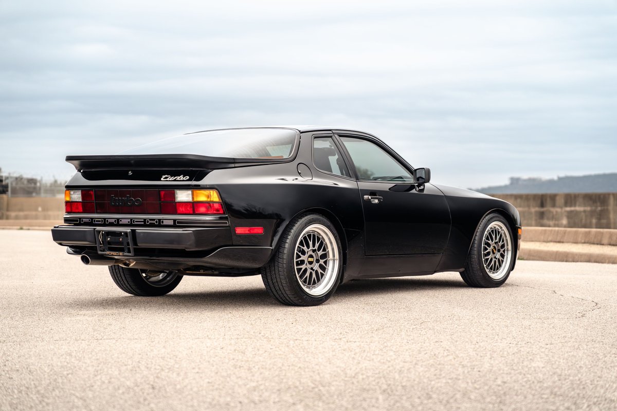 Black 1986 Porsche 944 Turbo rear 3/4 view, showing Turbo script, rear spoiler and mesh rims.