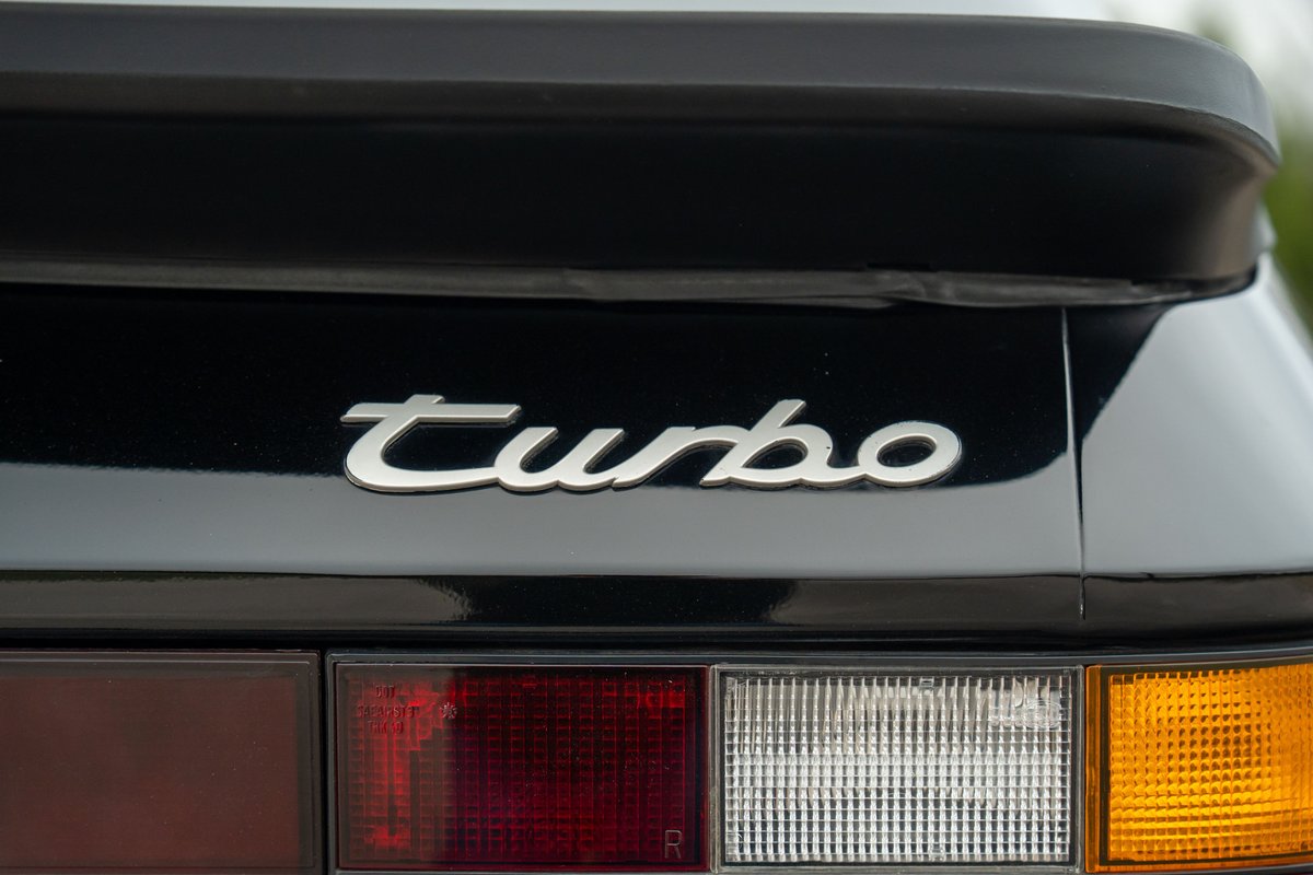 Close-up of a black 1986 Porsche 944 Turbo's rear badge and taillights.