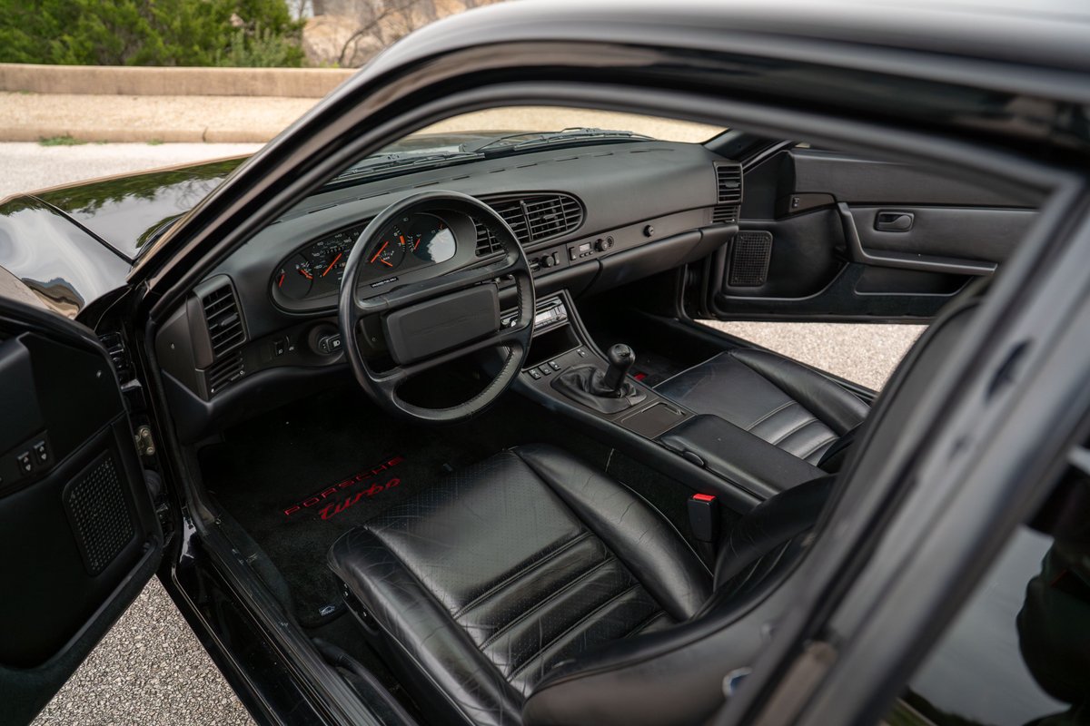 Black 1986 Porsche 944 Turbo interior with leather seats and floor mats.