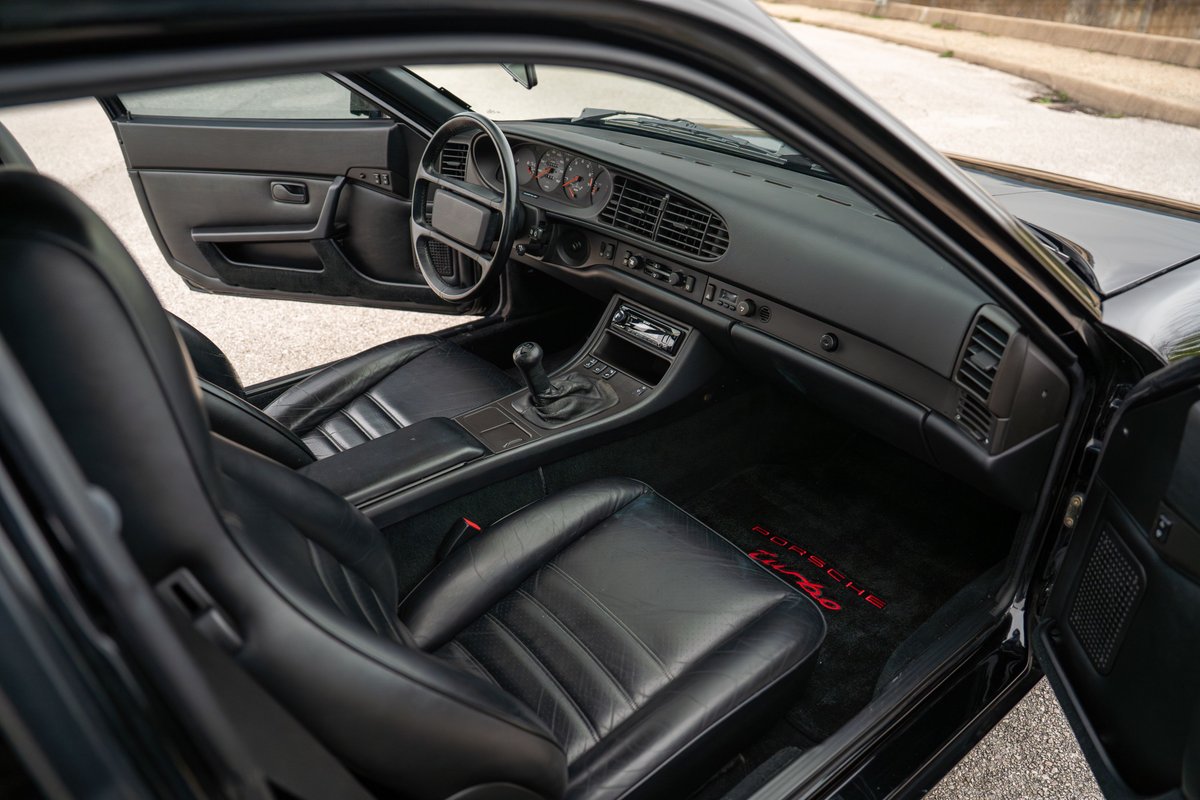 Black 1986 Porsche 944 Turbo interior. Leather seats, dashboard, and floor mats with "Porsche Turbo" branding.