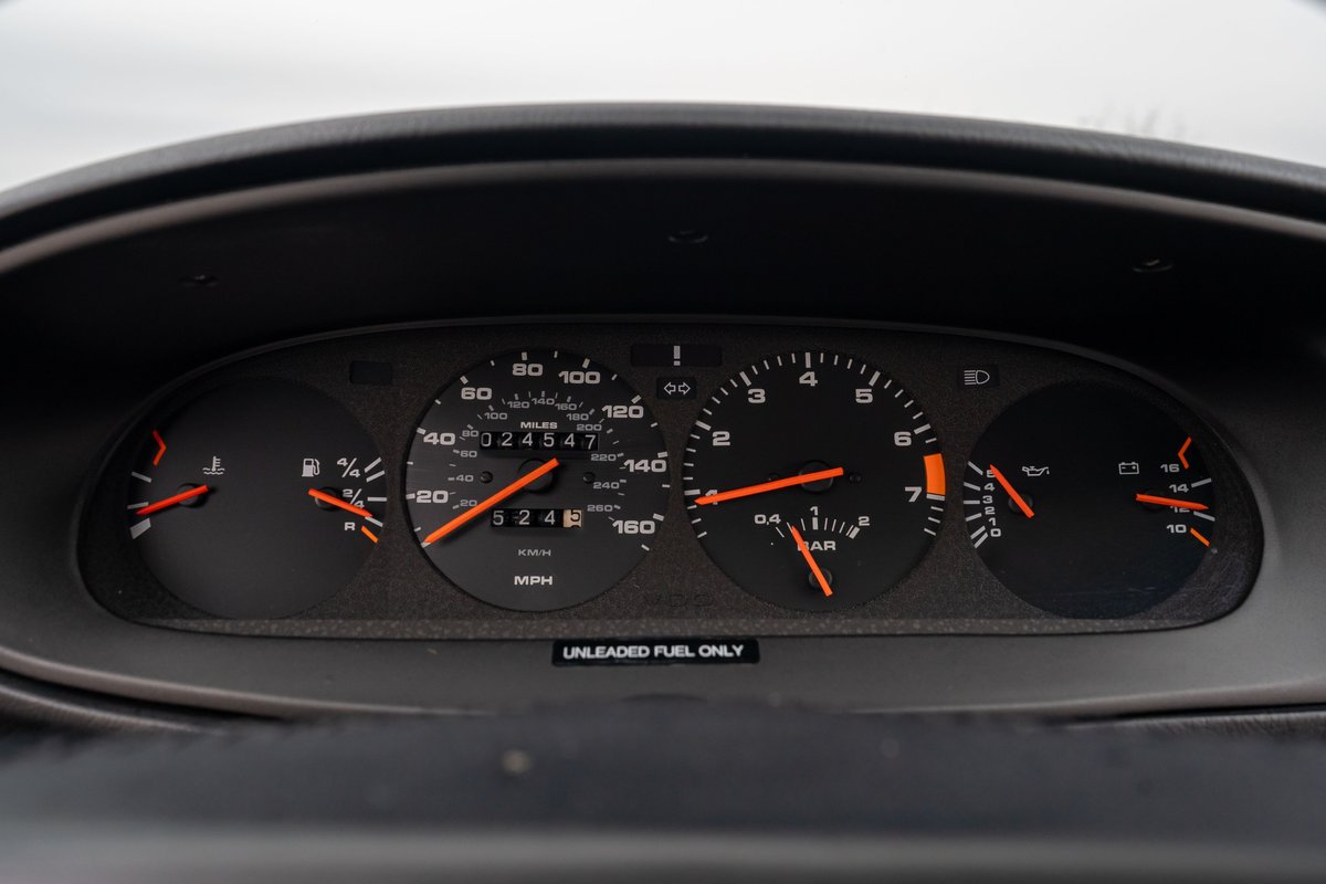 Close-up of the dashboard of a black 1986 Porsche 944 Turbo, showing the gauges and mileage.