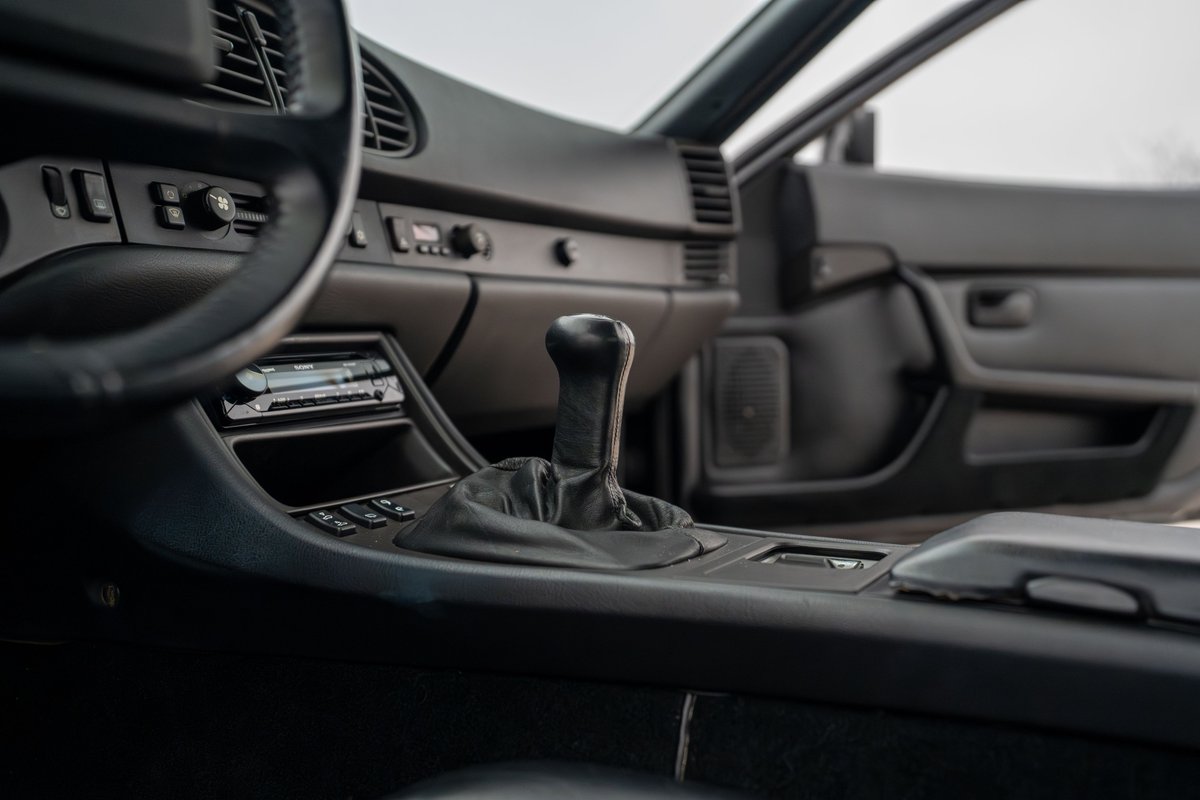 Black 1986 Porsche 944 Turbo interior with manual shifter and aftermarket stereo.